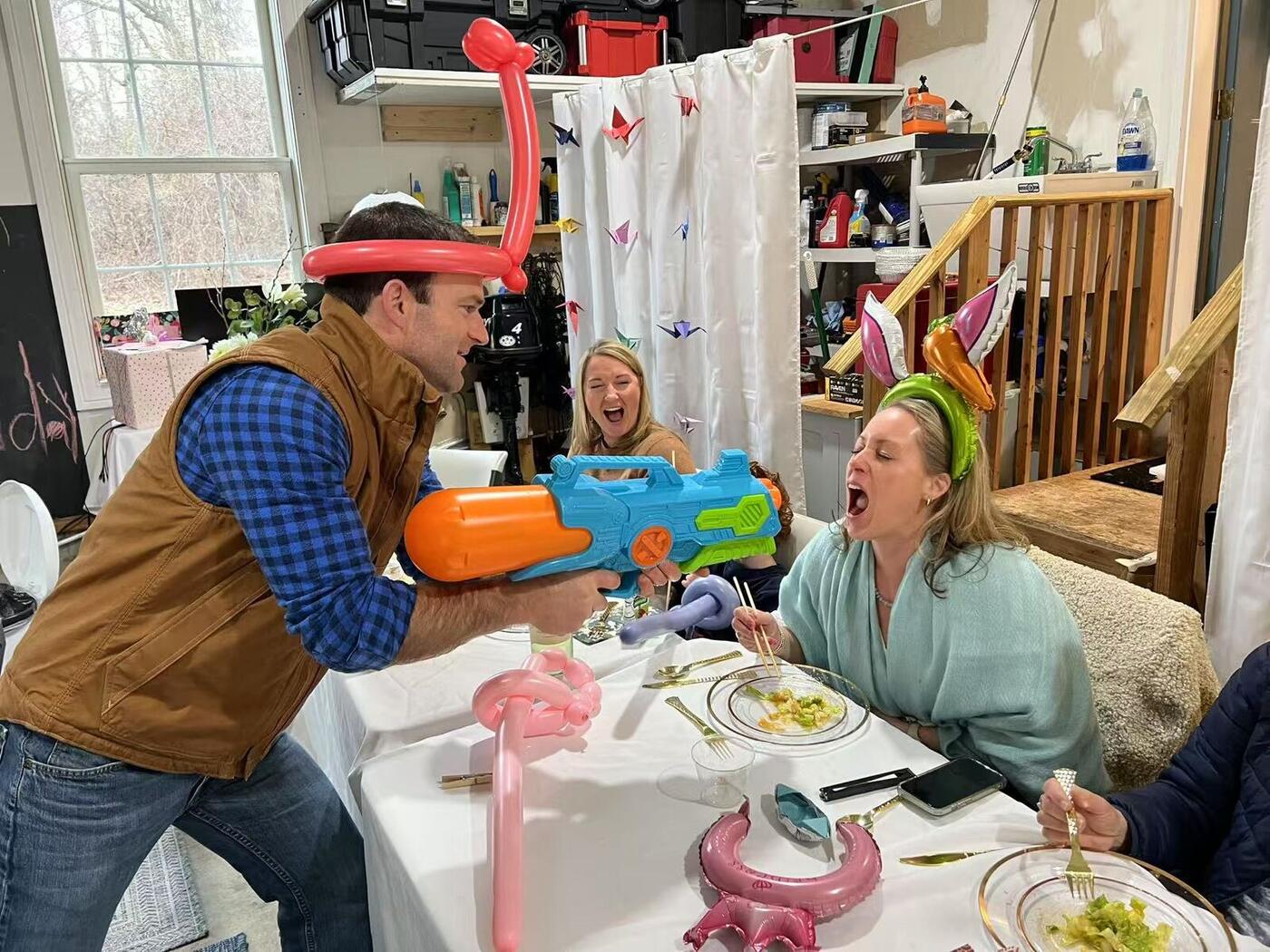 Happy Hibachi chef having water gun fun with guests at a Long Island home party