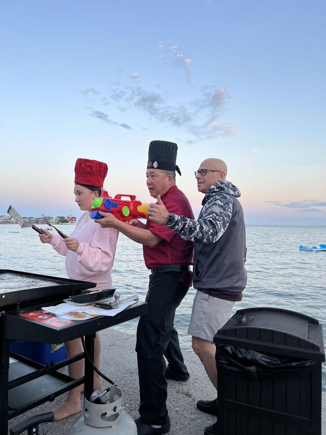Hibachi chefs having fun with a guest at a waterfront sunset party on Long Island