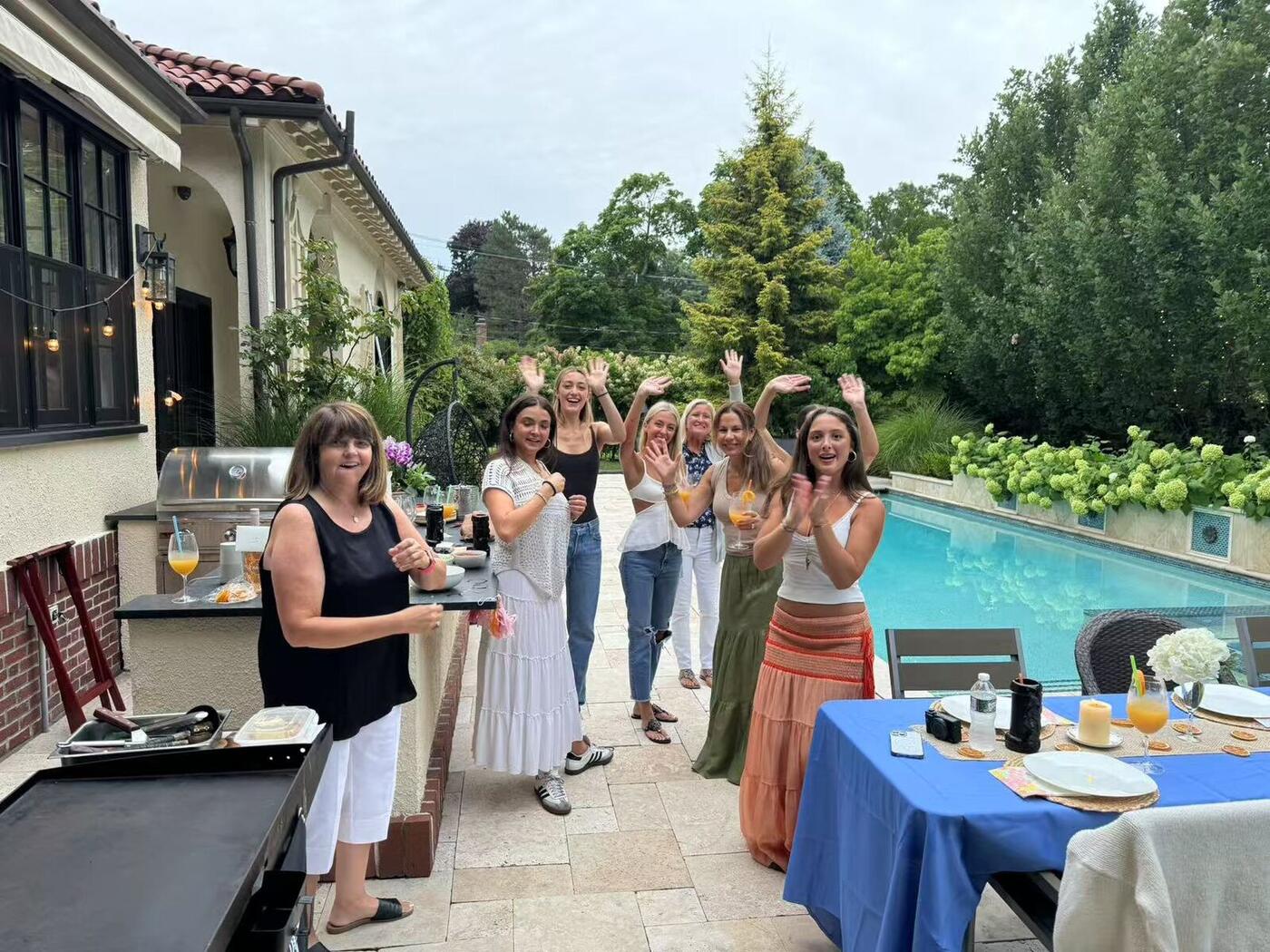 Guests waving at a poolside hibachi dinner party in Nassau County